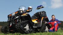 Ein Mitarbeiter der Bergwacht neben einem Quad Motorrad mit Ketten statt Rädern.